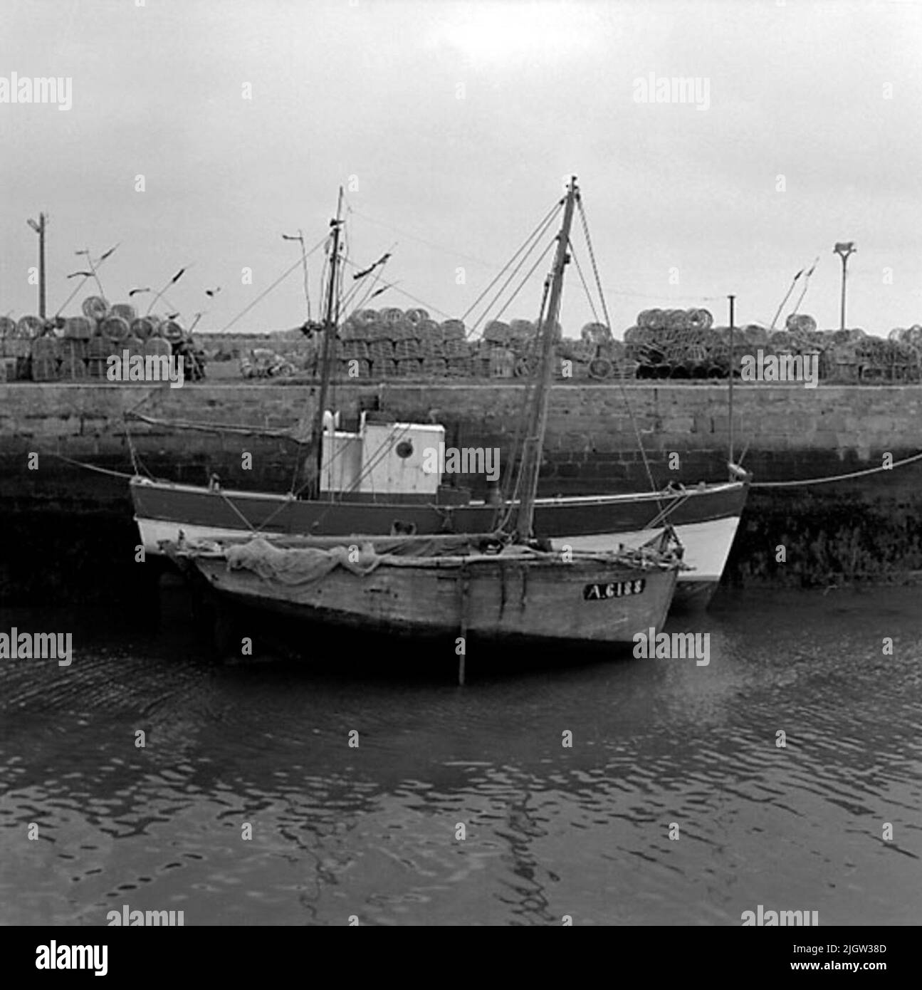 7. France. Photo journal is available at B.M.A. + Photo albums. Acquisition: Books and archive materials. Photos taken 1959-10-16.12 Pictures in series. According to notes: France. Atlantic coast, Le Croisic, 17/10 -59. Fishing boats in the harbor channel under EBB. In the background Hummertinor.två fishing boat is located in a harbor. It is low tide so the boats are partly on the bottom. On the quay there are cages for fishing. Stock Photo