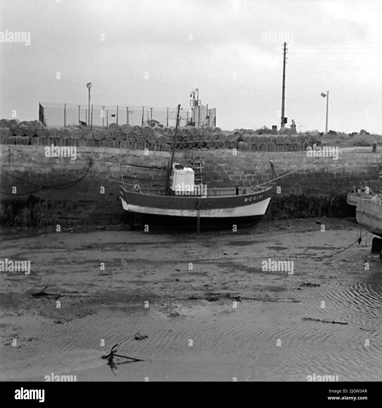 7. France. Photo journal is available at B.M.A. + Photo albums. Acquisition: Books and archive materials. Photos taken 1959-10-16.12 Pictures in series. According to notes: France. Atlantic coast, Le Croisic, 17/10 -59. Fishing boats in the harbor channel under EBB. In the background Hummertinor. Three boats are located in a harbor. It is low tide so they rest on the bottom of the harbor. On the quay there are cages used in fishing. Stock Photo