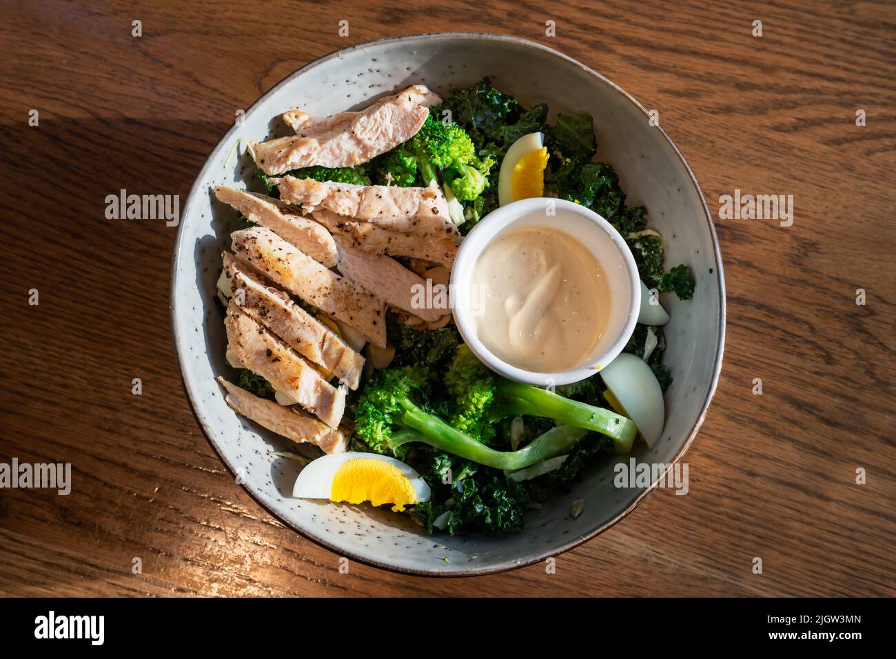 Mixed salad dish with chicken meat eggs and broccoli on a wooden table Stock Photo