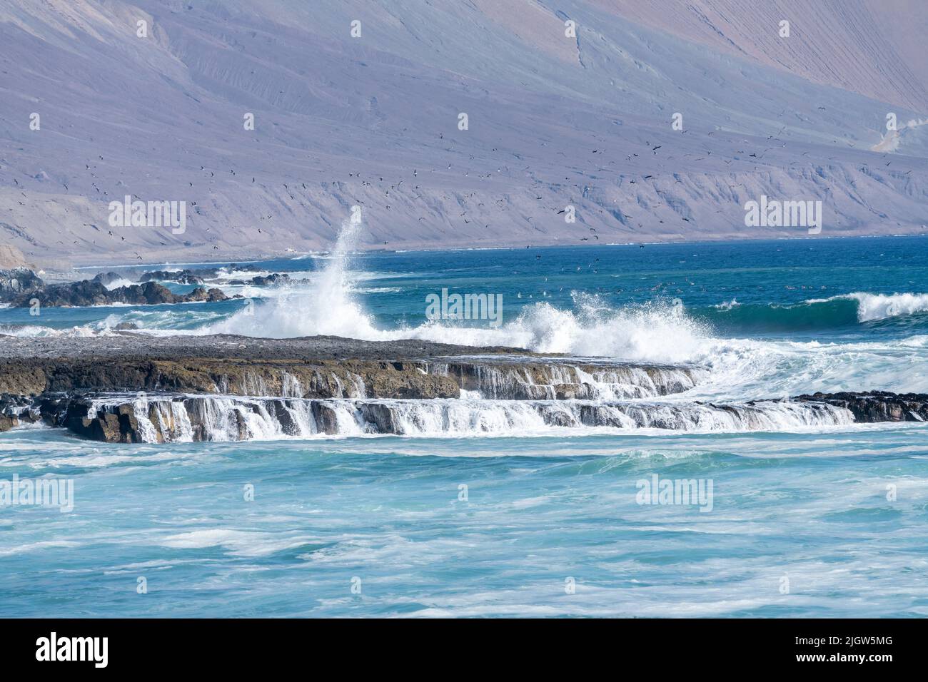 Waves crash on the rocky shoreline of tne coast of the Pacific Ocean