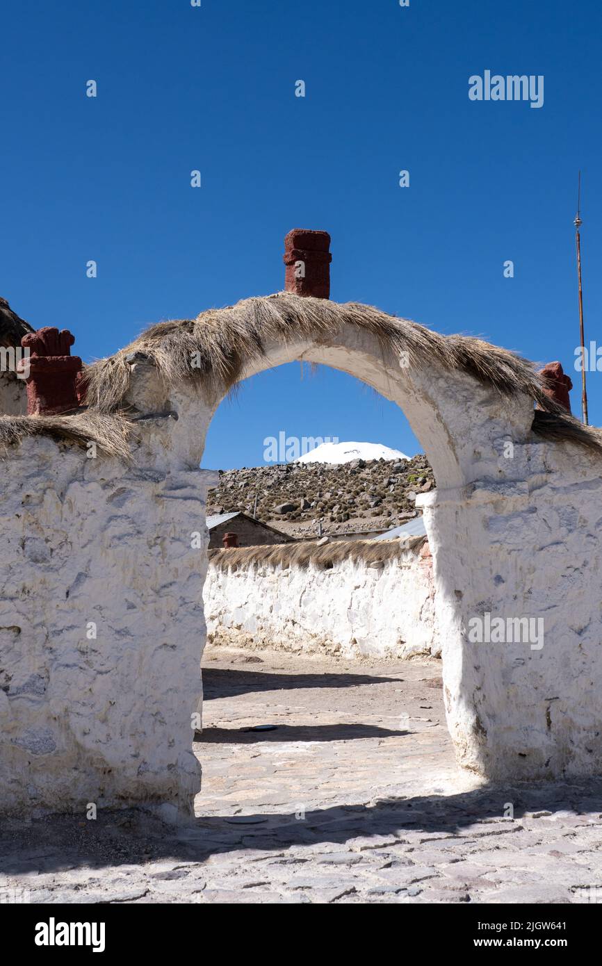 An arched entryway into the grounds of the Church of the VIrgin of the Nativity in the village of Parinacota in Chile.  Behind is the snow-capped peak Stock Photo