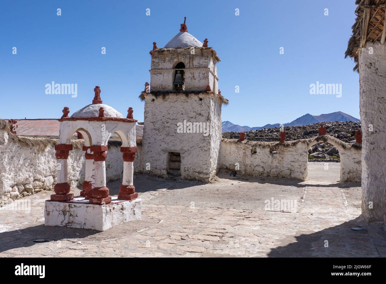 The stone bell tower of the Church of the Virgin of the Nativity in Parinacota on the Andean altiplano in Chile.  Behind is Cerro Larancagua. Stock Photo
