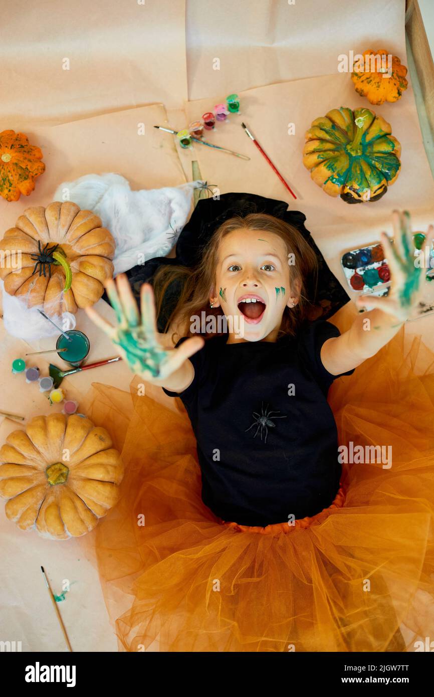 Top view of Smiling girl lying on the floor between drew pumpkin