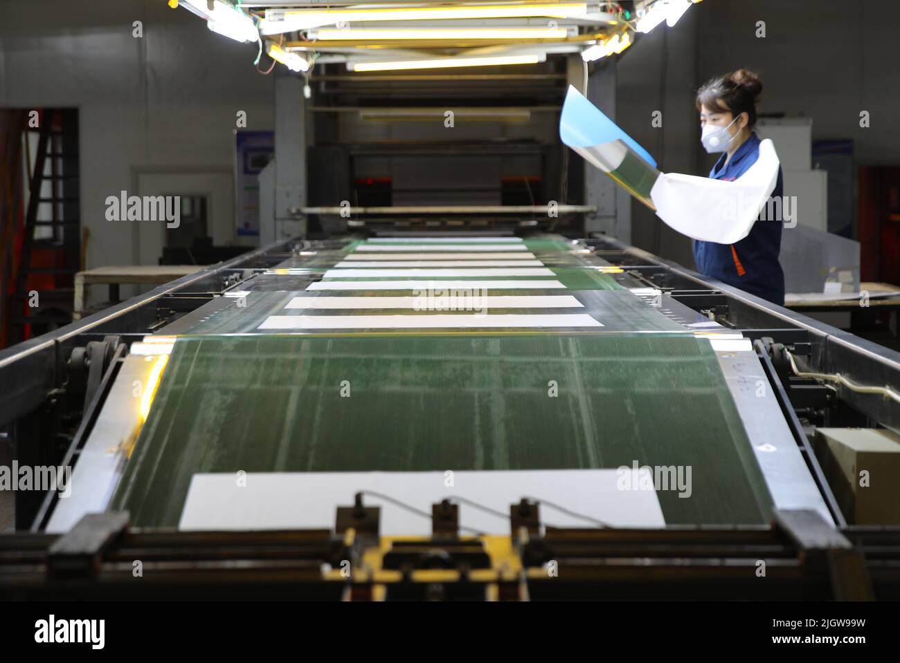 CHENGDE, CHINA - JULY 11, 2022 - A worker checks the quality of photosensitive coating on printing plate at a printing plate processing factory in Che Stock Photo