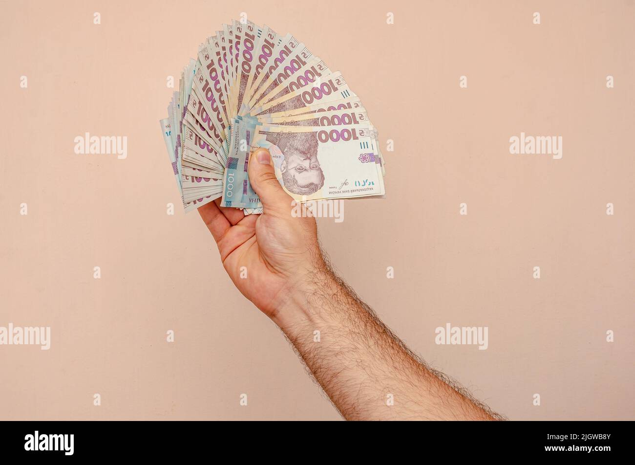 Man hand holding Ukrainian hryvnia bills of 1000 hryvnias. War in Ukraine, economic problems, earnings Stock Photo