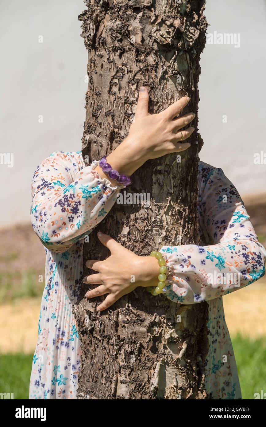 Detail of a woman's arms hugging a tree. Hugging a tree has many health