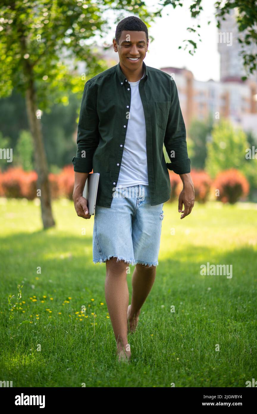 Man walking barefoot on grass in park Stock Photo