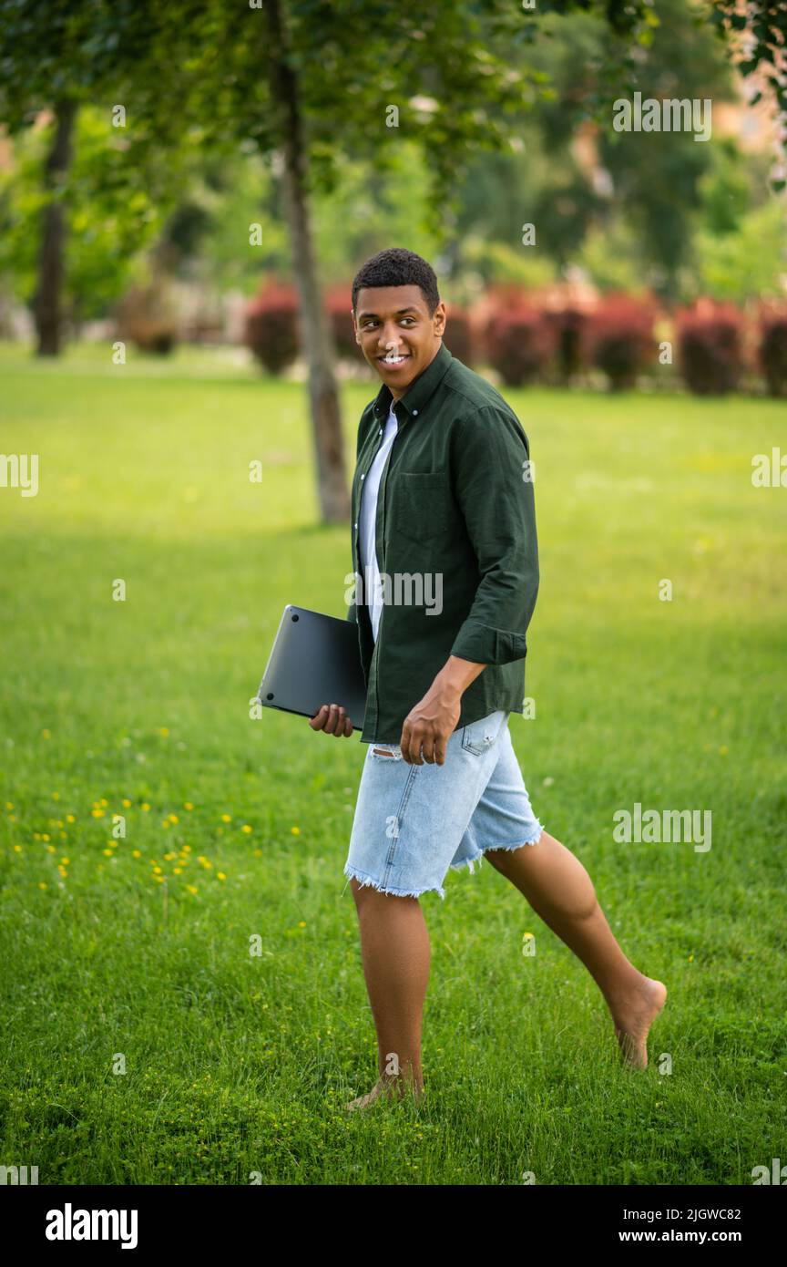 Man walking barefoot on grass sideways to camera Stock Photo