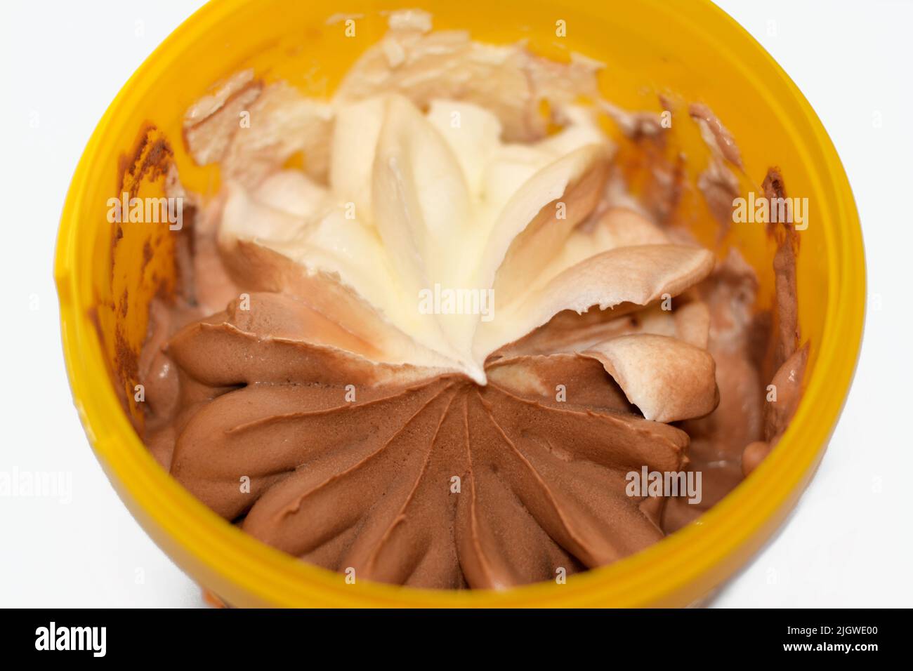 Frozen ice cream half vanilla and half chocolate in a plastic container