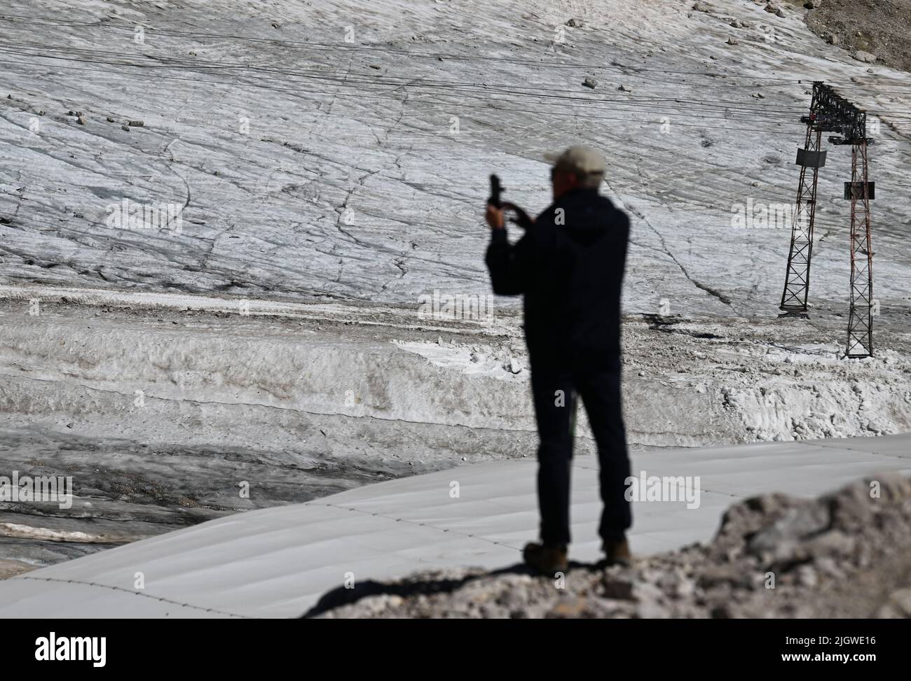 Grainau, Germany. 13th July, 2022. A hiker photographs the remnants of the Northern Schneeferner Glacier on the Zugspitzplatt. The warm temperatures affected the remnants of the glacier on Zugspitze this summer. Credit: Angelika Warmuth/dpa/Alamy Live News Stock Photo