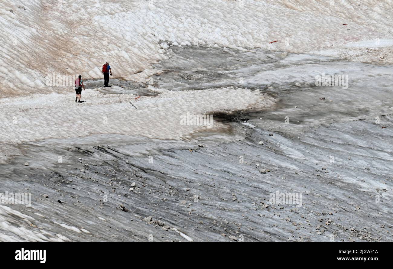 Grainau, Germany. 13th July, 2022. Hiking on the Zugspitzplatt over snow remnants on the Northern Schneeferner Glacier. The warm temperatures affected the glacier remnant on the Zugspitze this summer. Credit: Angelika Warmuth/dpa/Alamy Live News Stock Photo