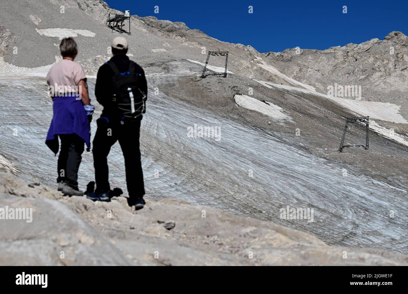 Grainau, Germany. 13th July, 2022. Hikers look at the remains of the Northern Schneeferner Glacier on the Zugspitzplatt. The warm temperatures affected the remnants of the glacier on Zugspitze this summer. Credit: Angelika Warmuth/dpa/Alamy Live News Stock Photo