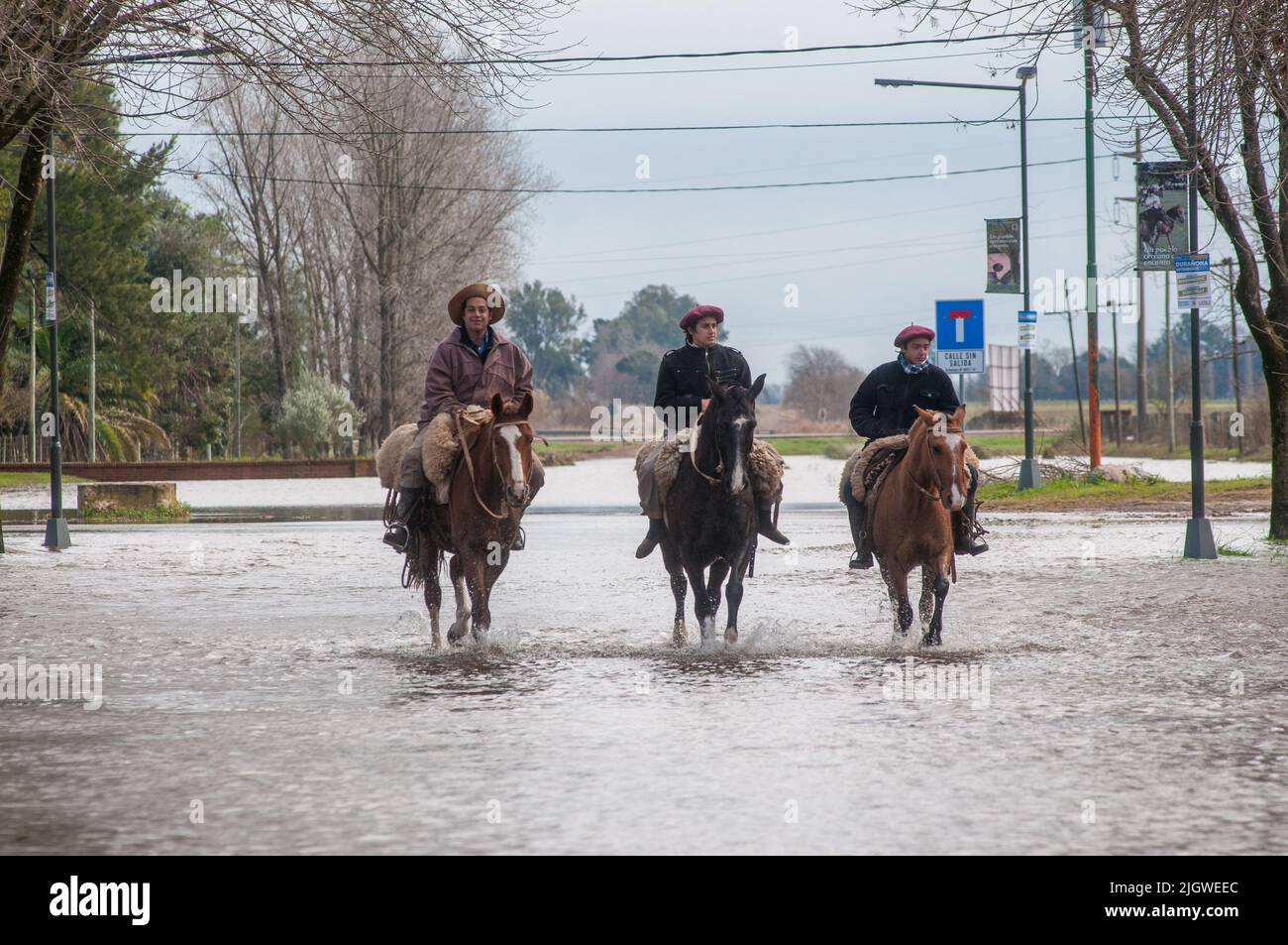 The Hispanic men riding a horse on the street because of floods in San Antonio de Areco, Buenos Aires, Argentina Stock Photo