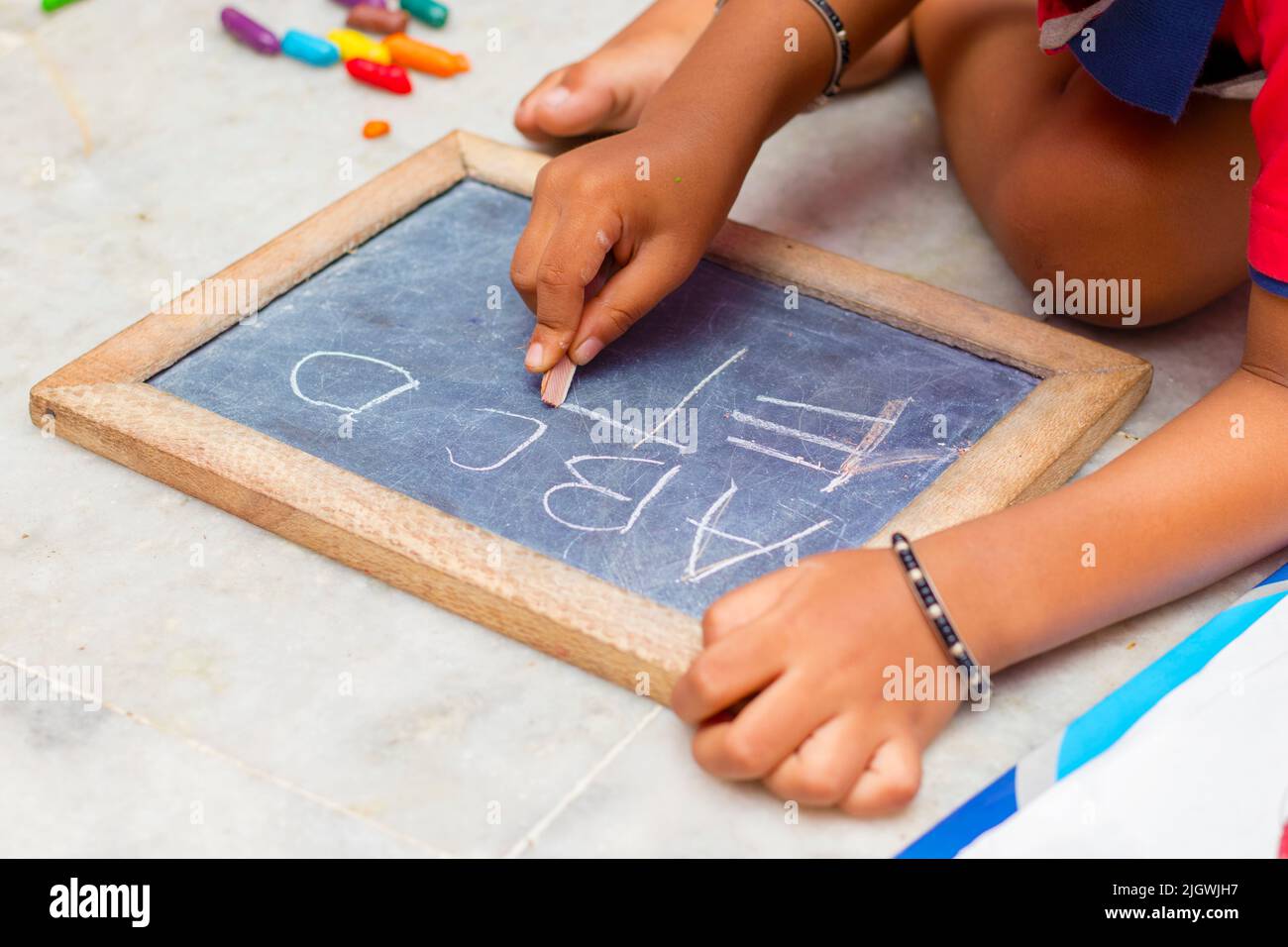 a baby child writing on a graphite slate. Stock Photo