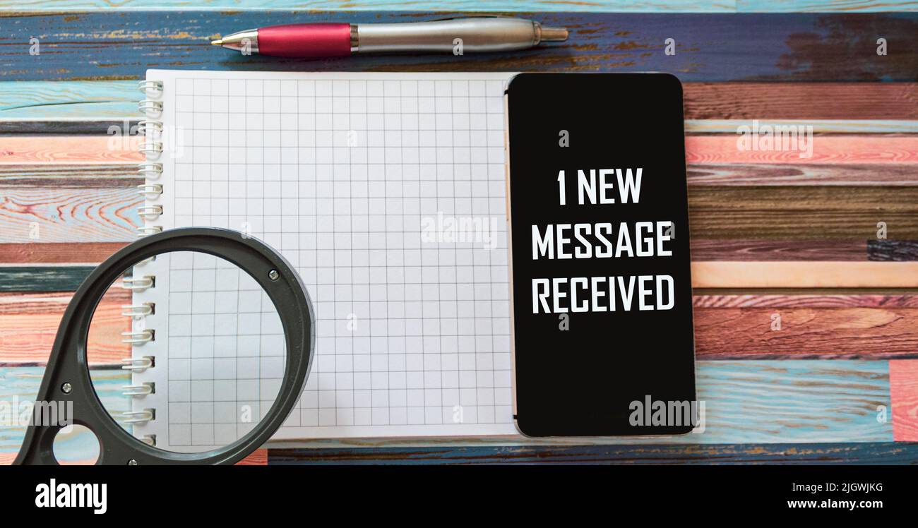 Mobile phone with a message about One new message received on a table ...