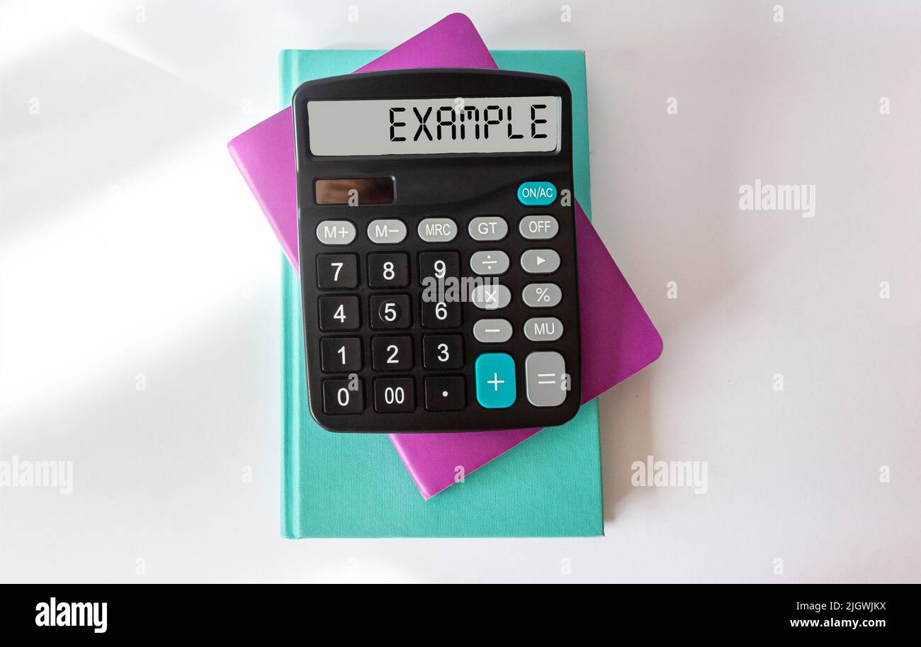 On a white table is a calculator labeled EXAMPLE. business concept Stock Photo