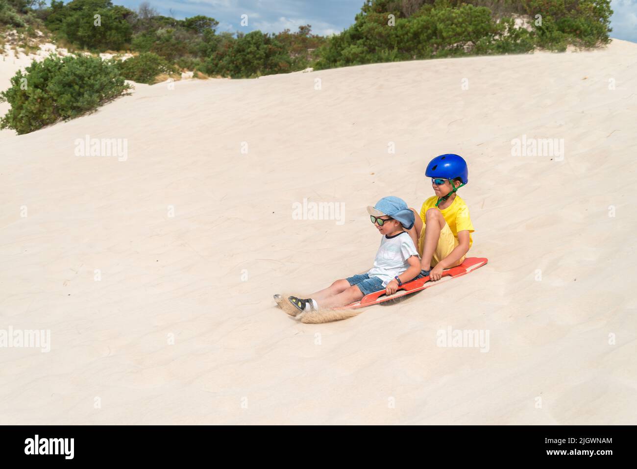 Children having fun while sliding down a sand dune on a sandboard, Kangaroo Island, South