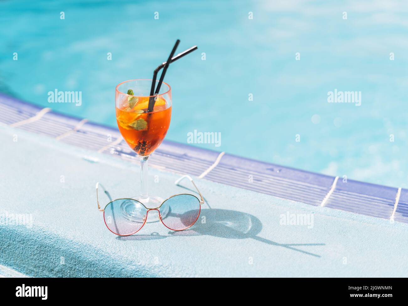 Glass of cocktail with ice and sunglasses on hotel pool, summer ...