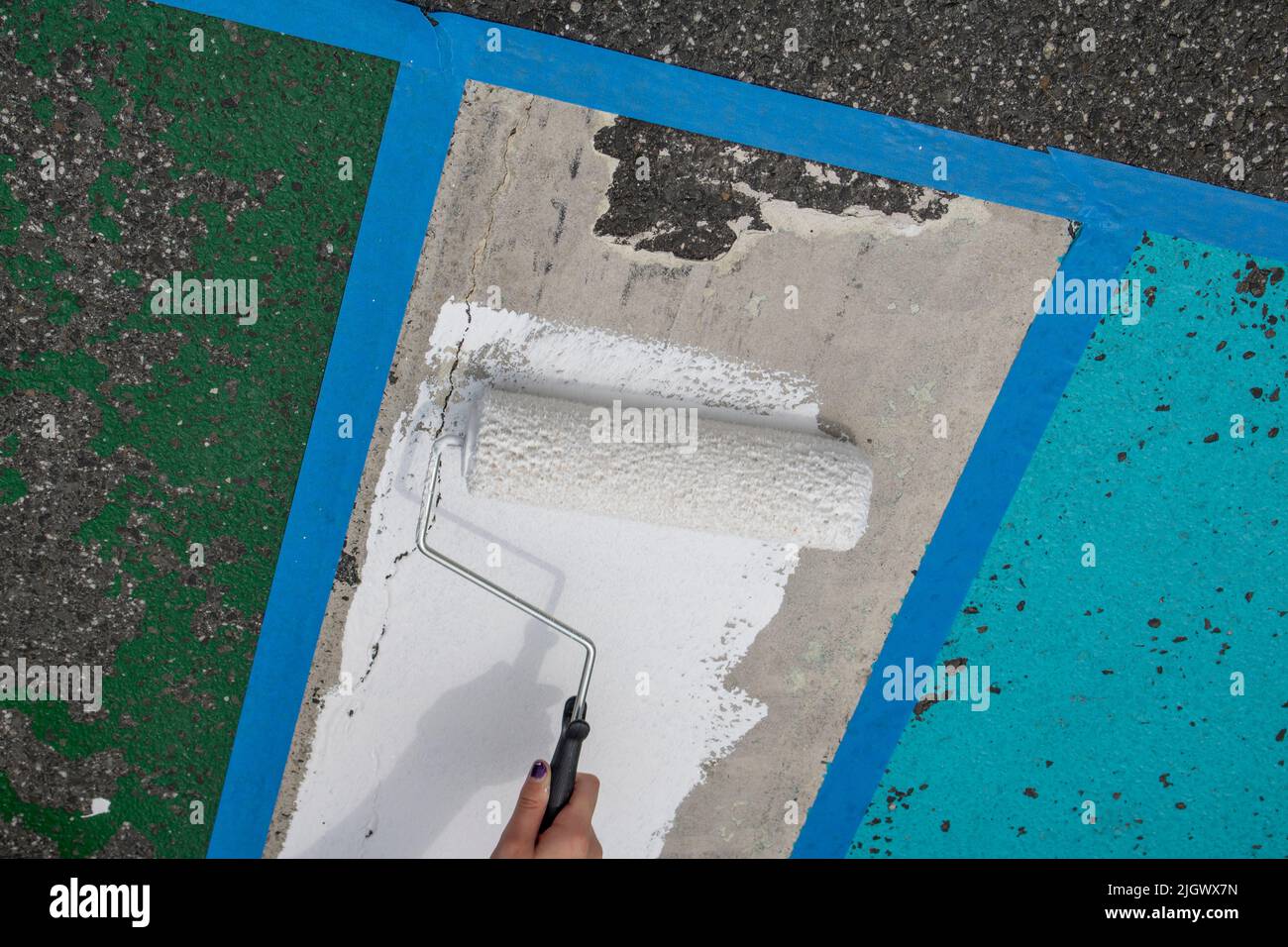 person painting with a white paint roller in hand Stock Photo