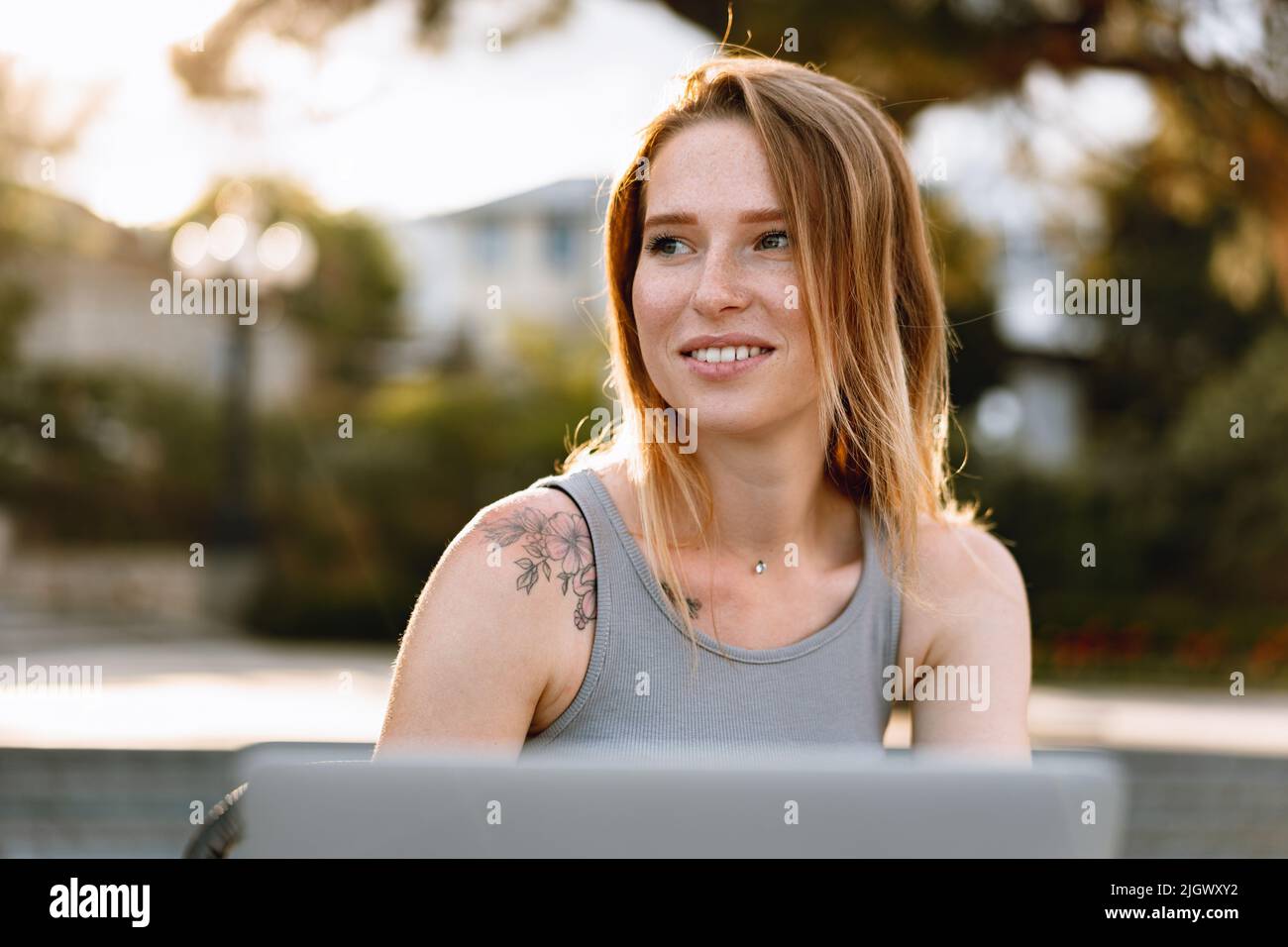 Happy beautiful young woman working on laptop in street cafe Stock ...