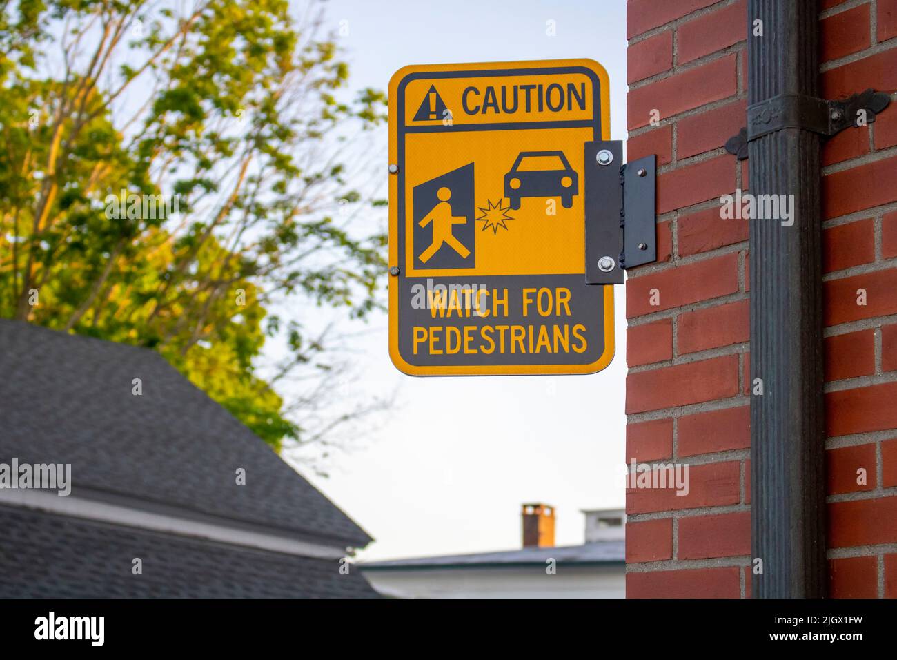 Caution watch for pedestrians yellow black street sign with figure and car graphics and star where injury may occur Stock Photo