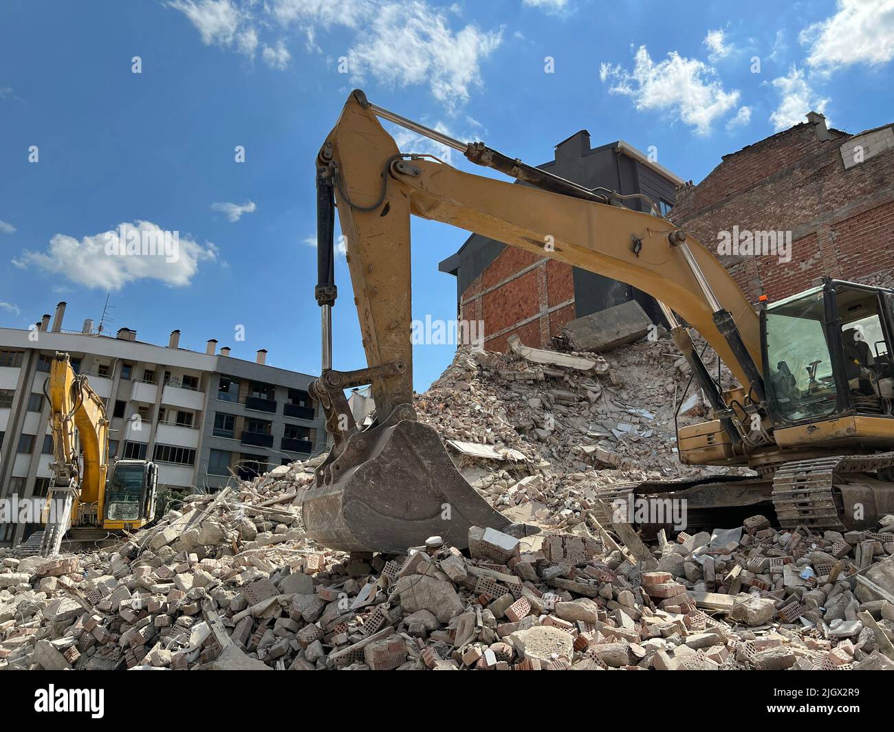 Demolition of building, two excavators are on the demolition of building. Construction site is opening for new buildings. Old buildings being demolish. Stock Photo