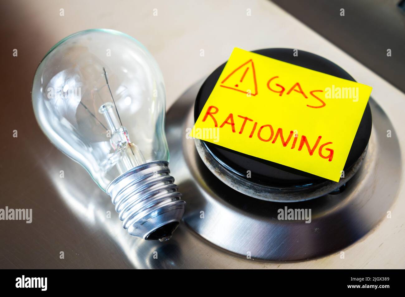 Gas stove, with yellow note next to it with text "gas rationing" and light bulb off. Rationing and insufficiency in gas flows. Energy crisis. Stock Photo