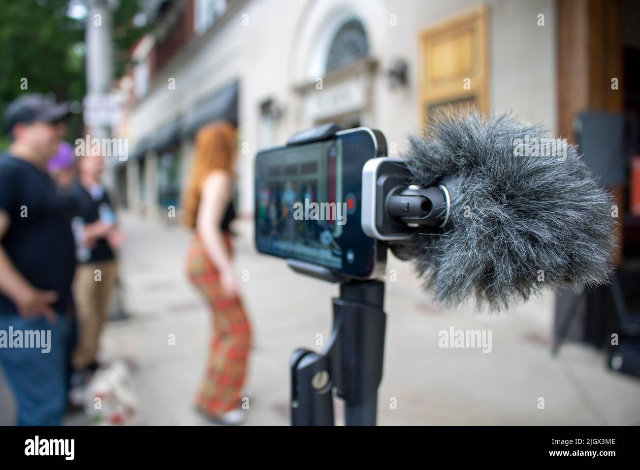 Digital Cardioid Microphone on smartphone recording band with a typhoid while groupies dance Stock Photo