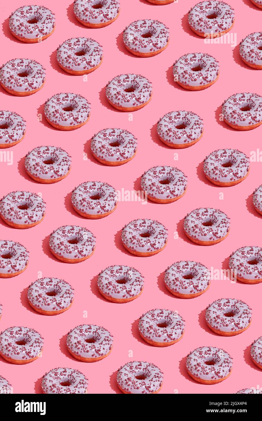 Food design with tasty pink glazed donut on coral pink pastel background top view pattern Stock Photo