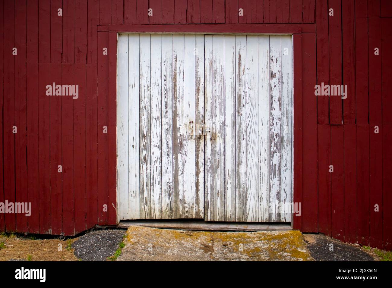 FARM HOUSE WHITE DISTRESTED DIUBLE DOORS on a red painted plank bard Stock Photo