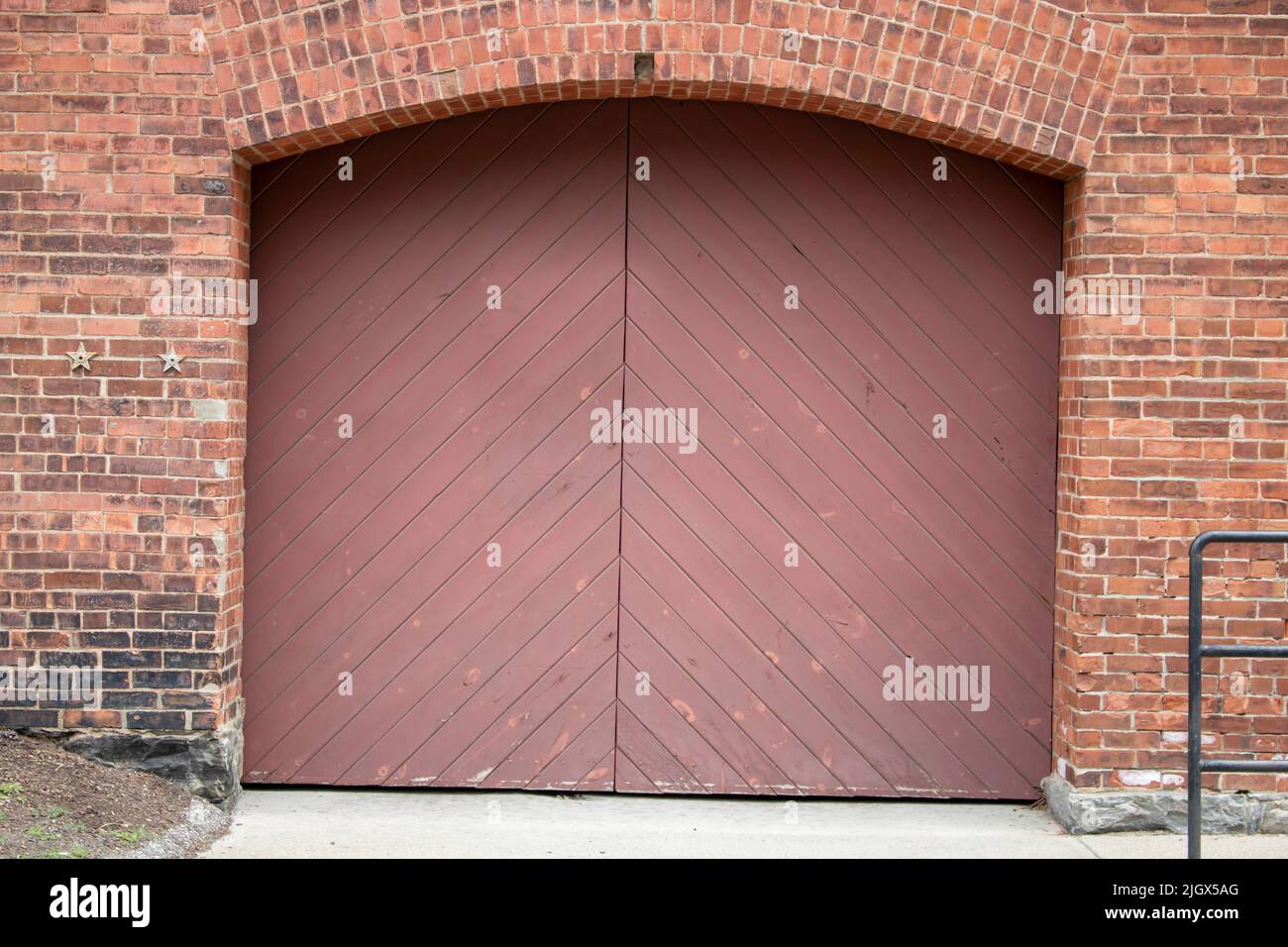 red painted wood double door entrance of the brick structure Stock Photo