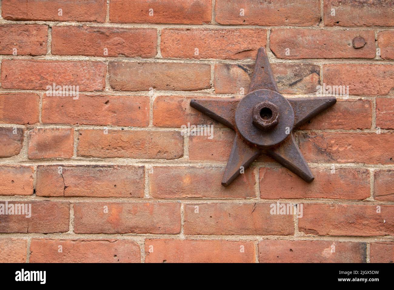 decorative and structural metal bolted stars on older brick building which suport the wall Stock Photo