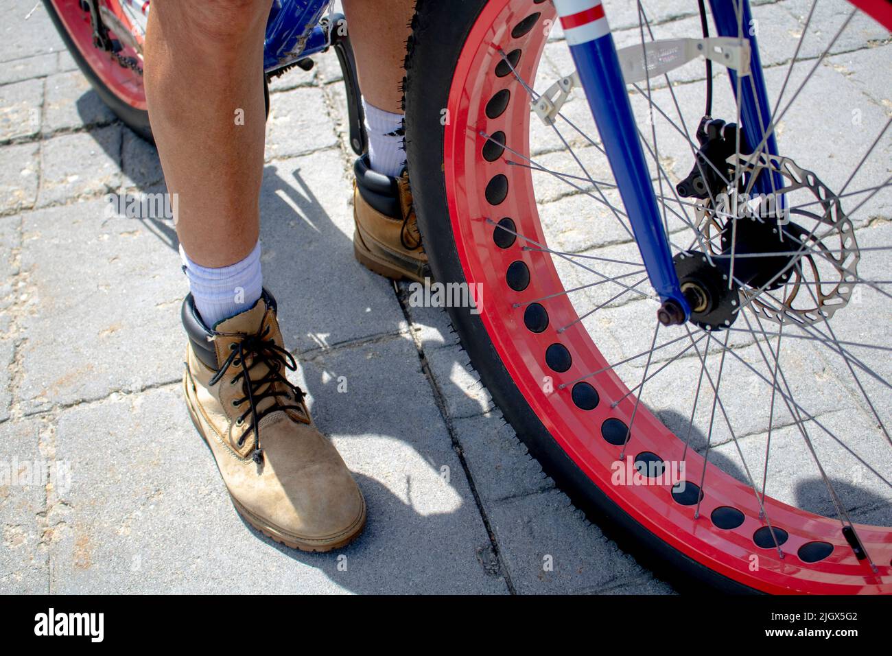 man in workbooks riding a fat tire bicycle with red rims ebike or
