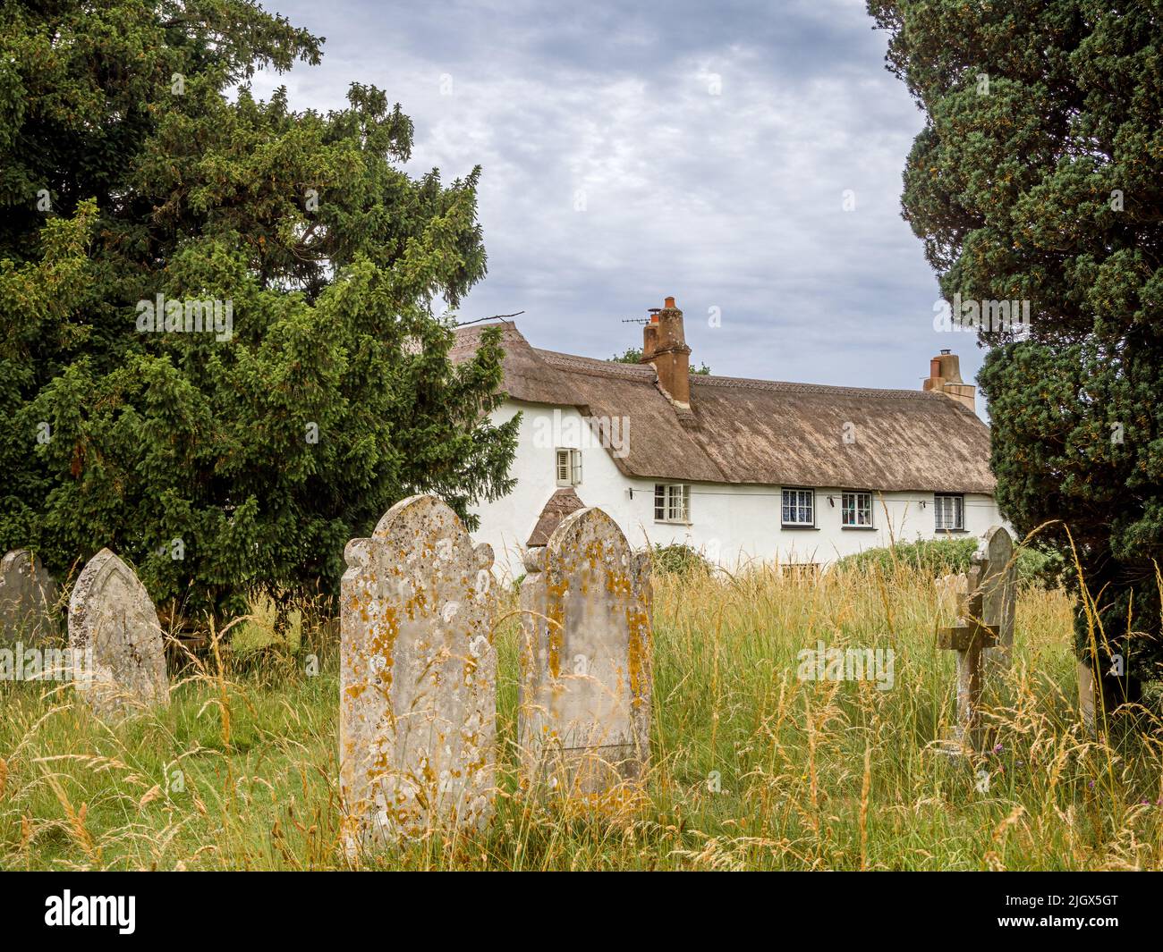 Thatched cottage alongside the churchyard in Woodbury, Devon Stock Photo