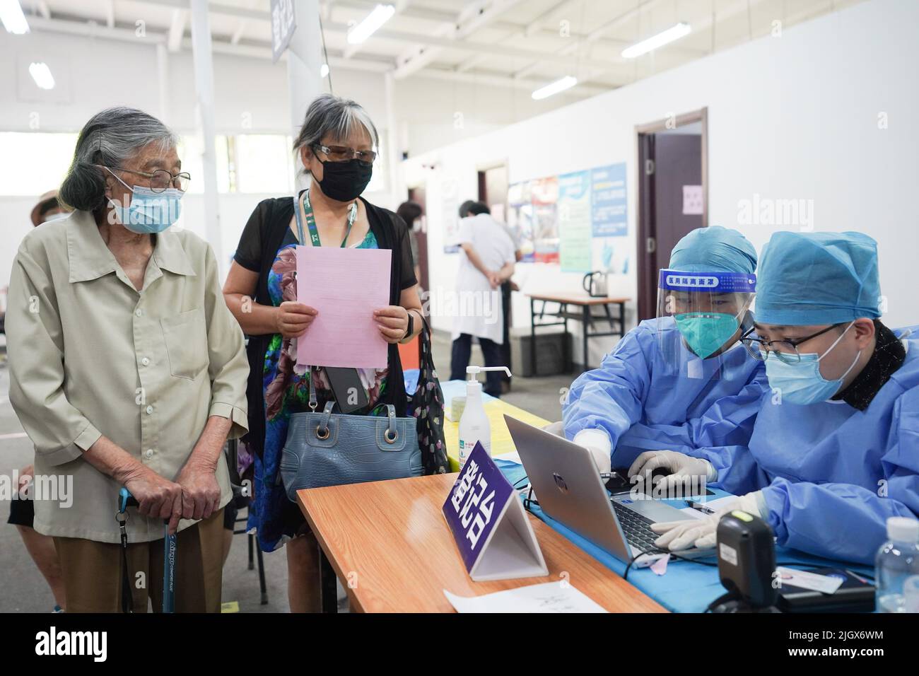 (220713) -- BEIJING, July 13, 2022 (Xinhua) -- A medical worker registers for an 89-year-old citizen (1st L) waiting to receive a booster shot of COVID-19 vaccine at Aoyuncun Subdistrict in Chaoyang District, Beijing, capital of China, July 13, 2022. Inoculation of the COVID-19 vaccine for the elderly has steadily advanced in Beijing. (Xinhua/Ju Huanzong) Stock Photo