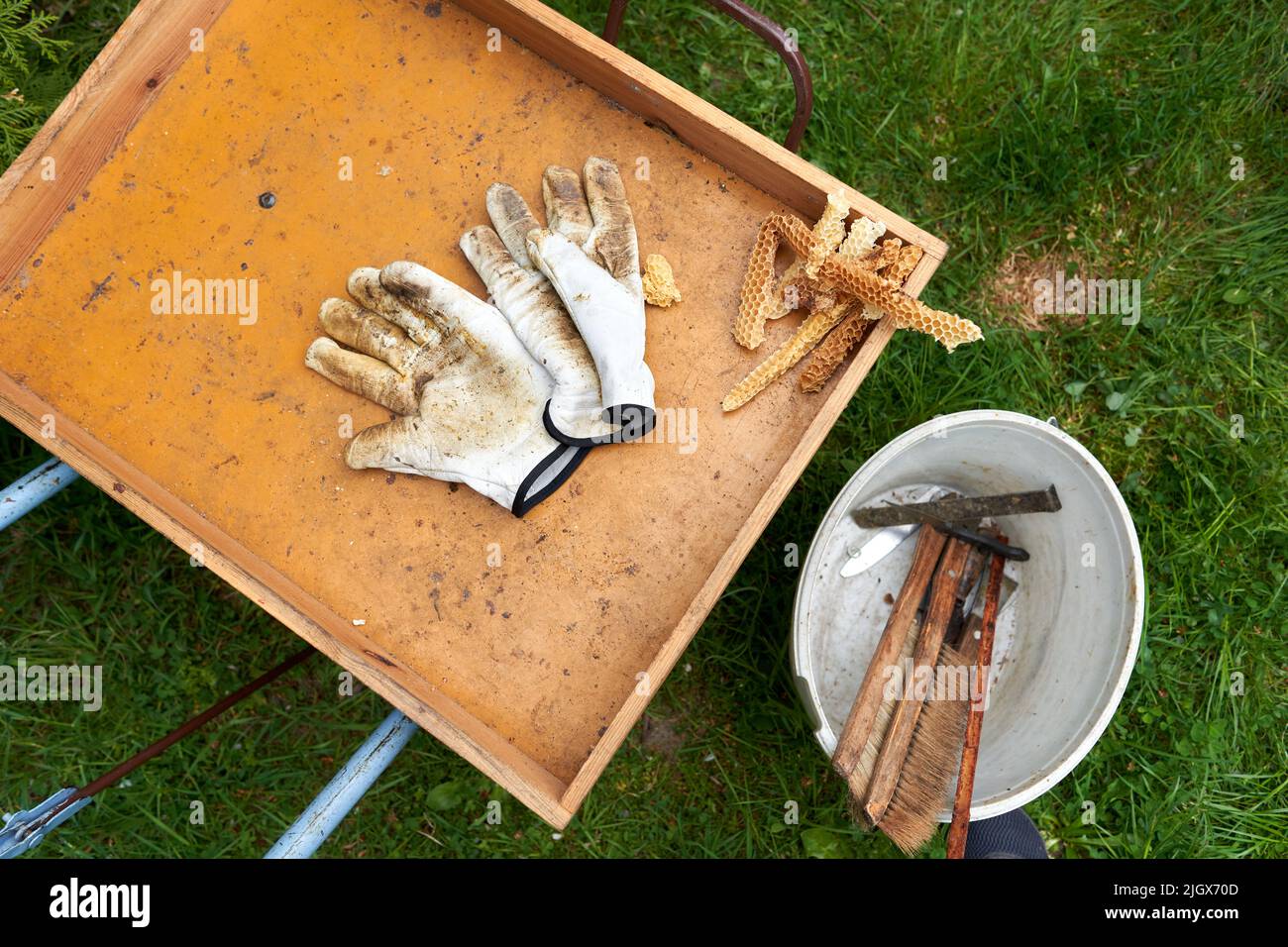 Wheelbarrow with protective gloves, tools and pieces of bee hive Stock Photo