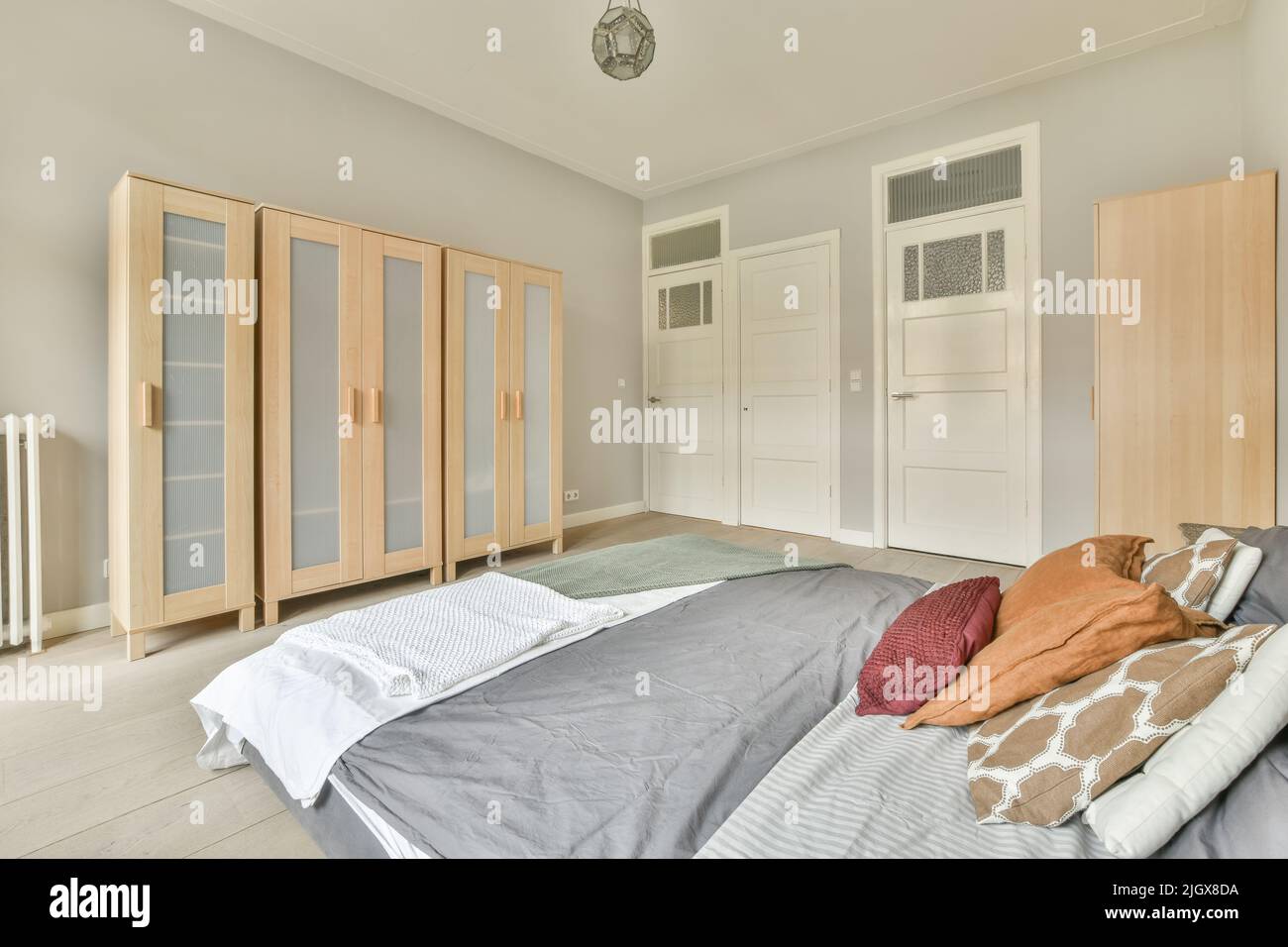 Comfortable bed with colorful pillows and warm blanket located near