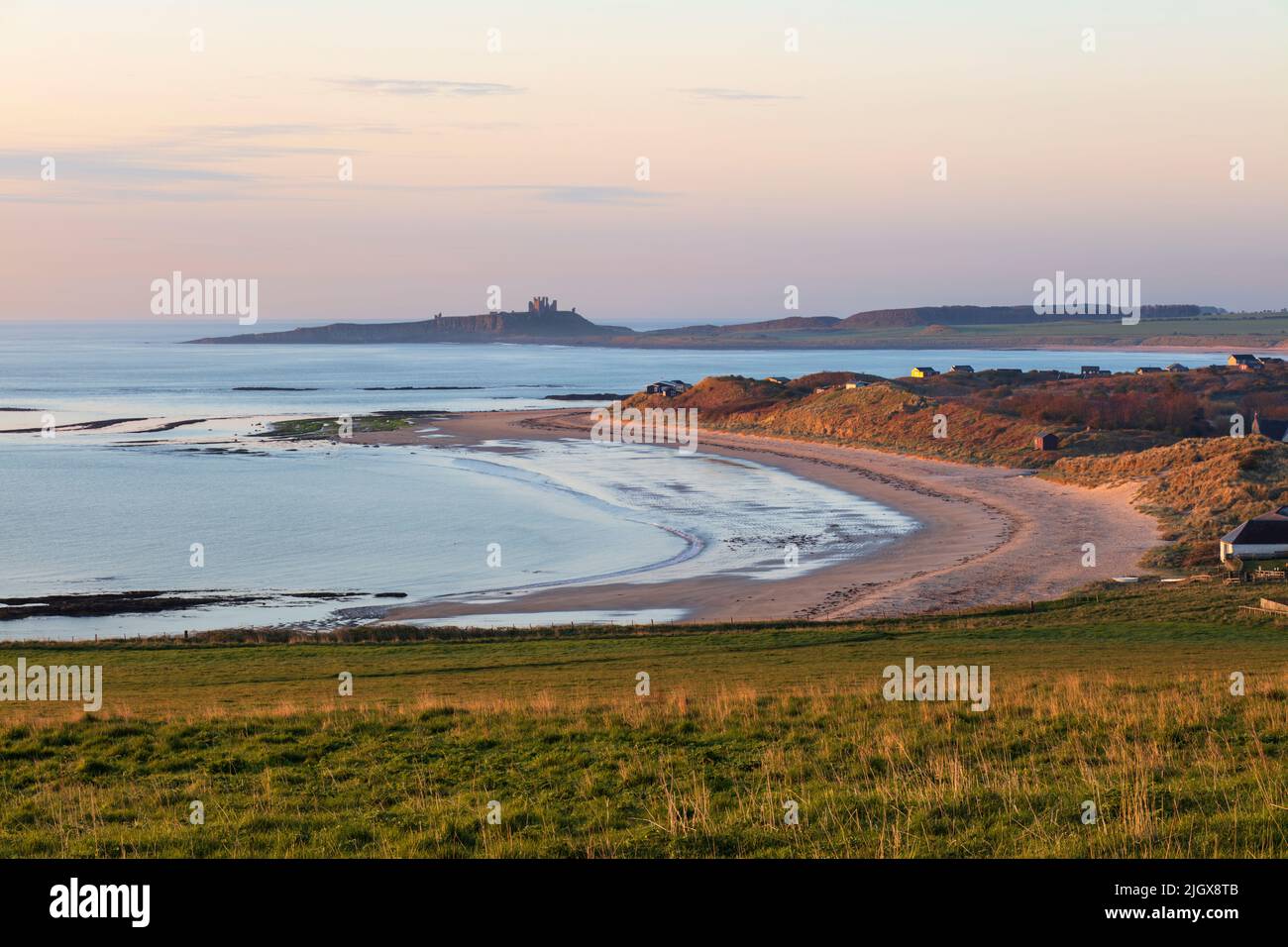 Low Newton-by-the-Sea beach with view to ruins of Dunstanburgh Castle at sunrise, Low Newton-by-the-Sea, Northumberland, England, United Kingdom Stock Photo
