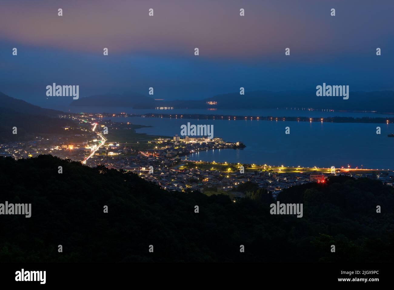 View of Amanohashidate land bridge and city lights in early evening Stock Photo