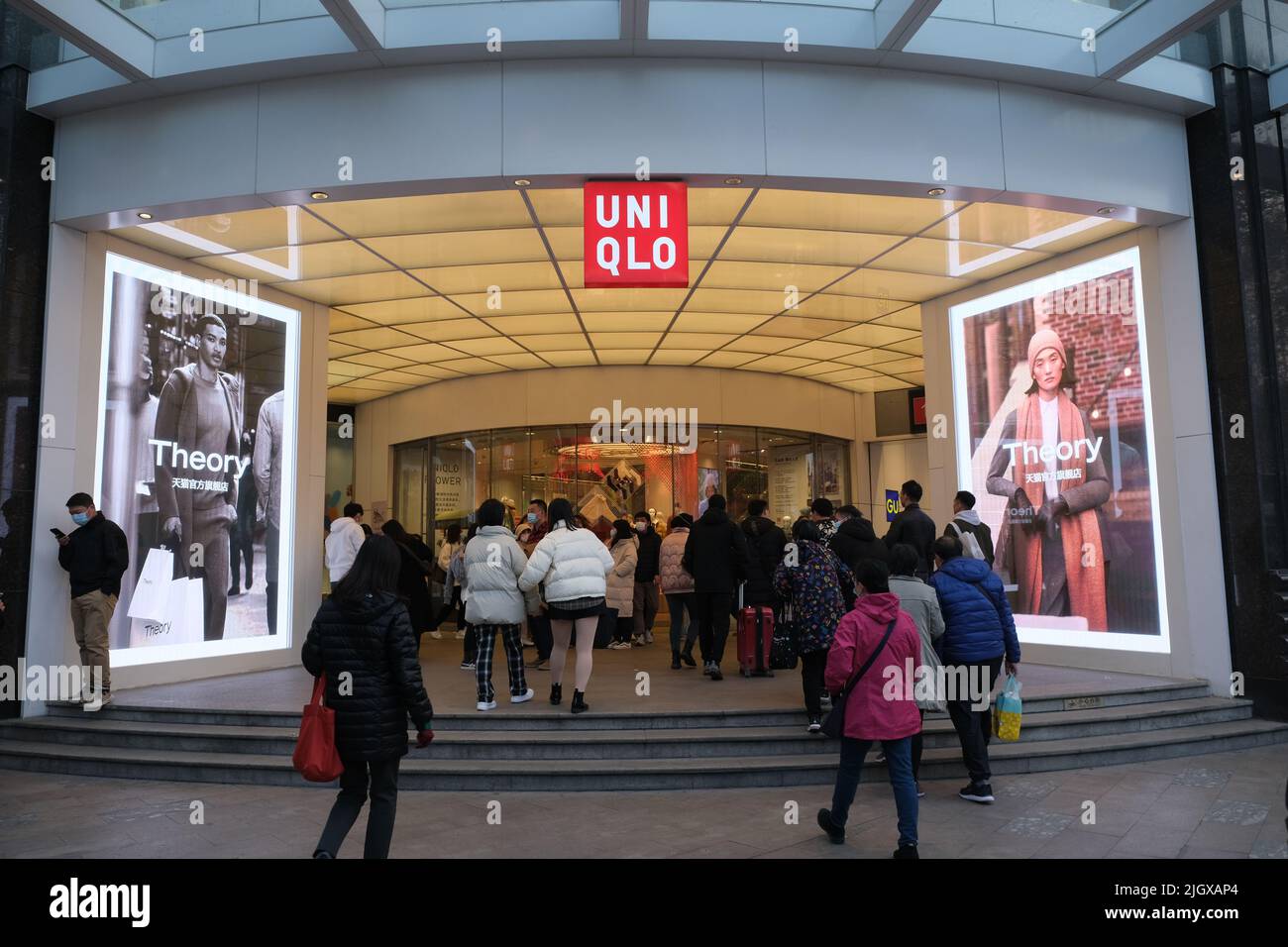 Shanghai,China-Jan.3rd 2022: many people walking into large Uniqlo clothing store. Facade of Uniqlo flagship store and brand logo Stock Photo