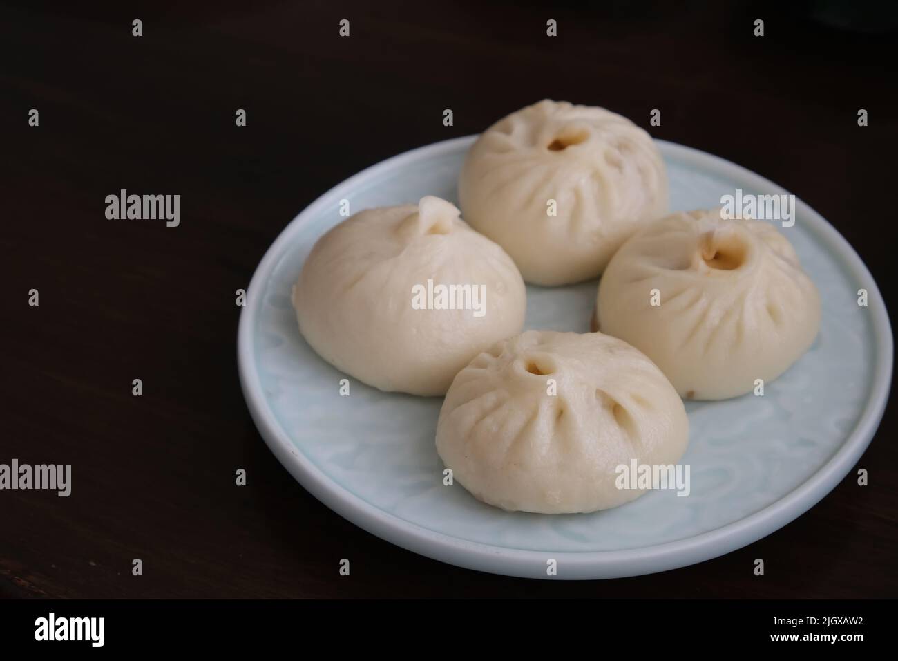 close up a plate of Chinese pan-fried pork buns (Sheng Jian Bao) on table. Traditional food Stock Photo