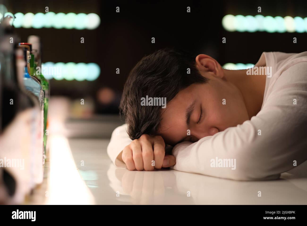 one handsome Asian young man drunk on bar counter at night Stock Photo