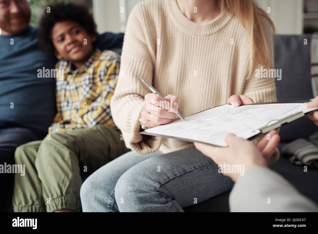 Close-up of young woman signing adoption contract with social worker during her visit to adoptive family Stock Photo