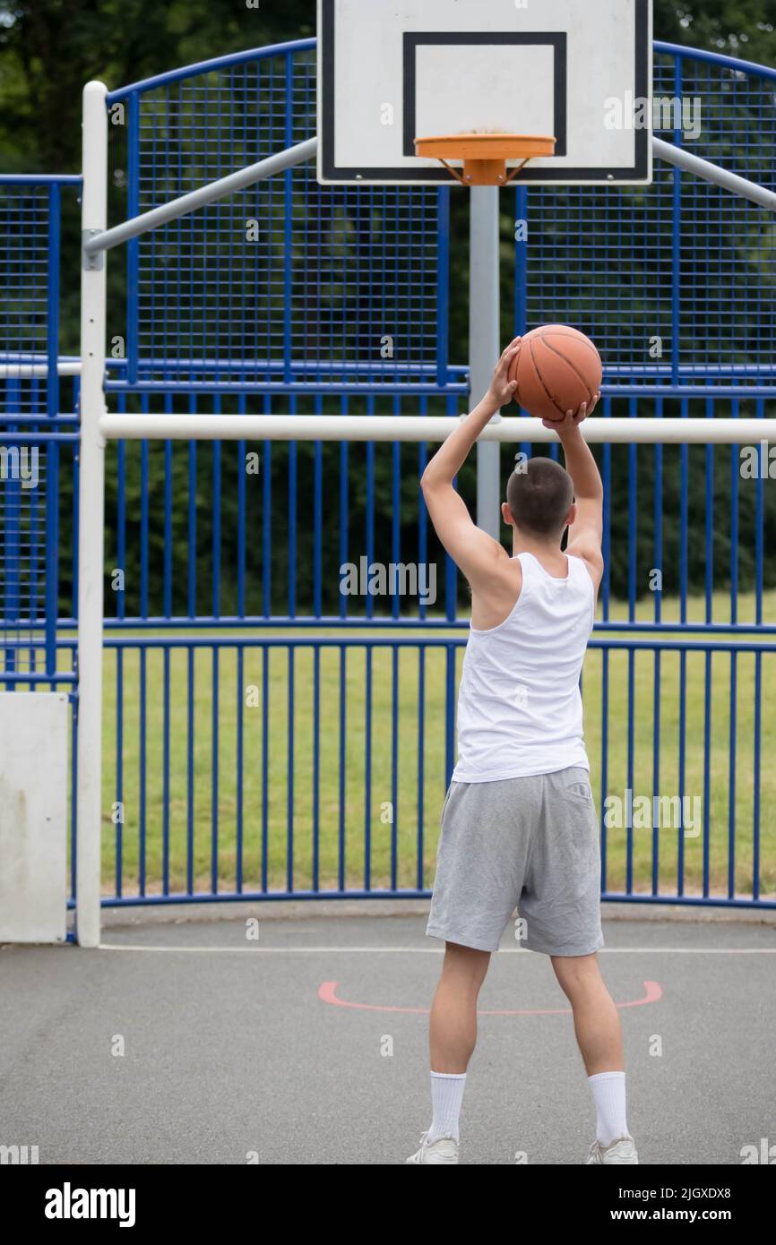 A Year Old Teenage Boy Shooting A Hoop in A Basketball Court