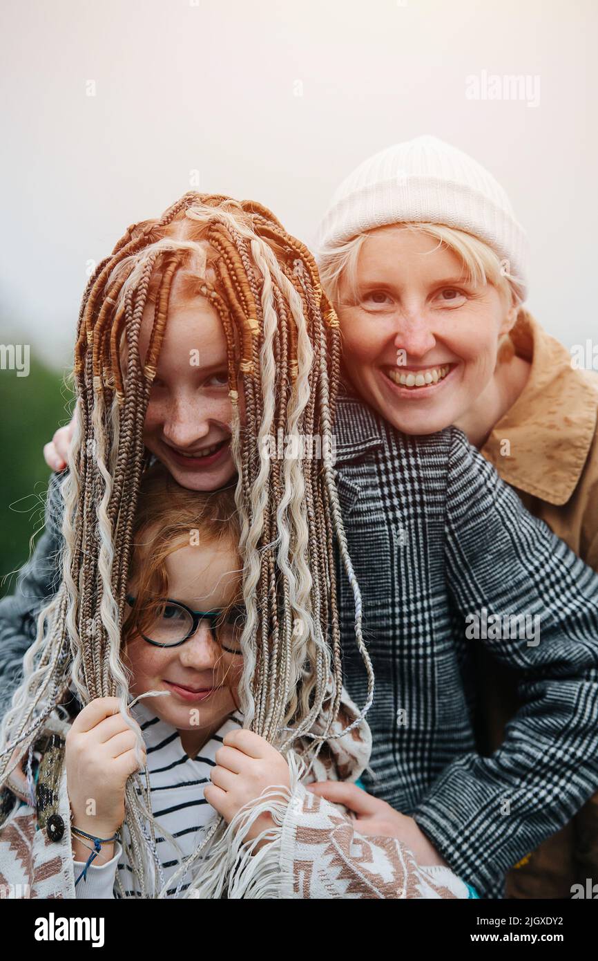 Close up family portrait. Mother and her daughters posing on a rainy day outdoors. Standing close to each other. Stock Photo