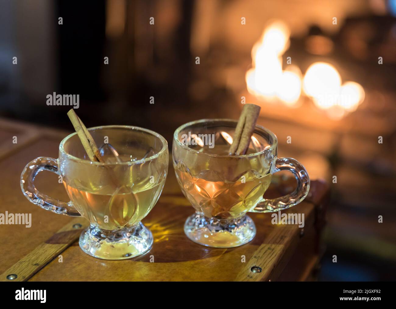 Two glass mugs of hot toddies in front of a fireplace Stock Photo