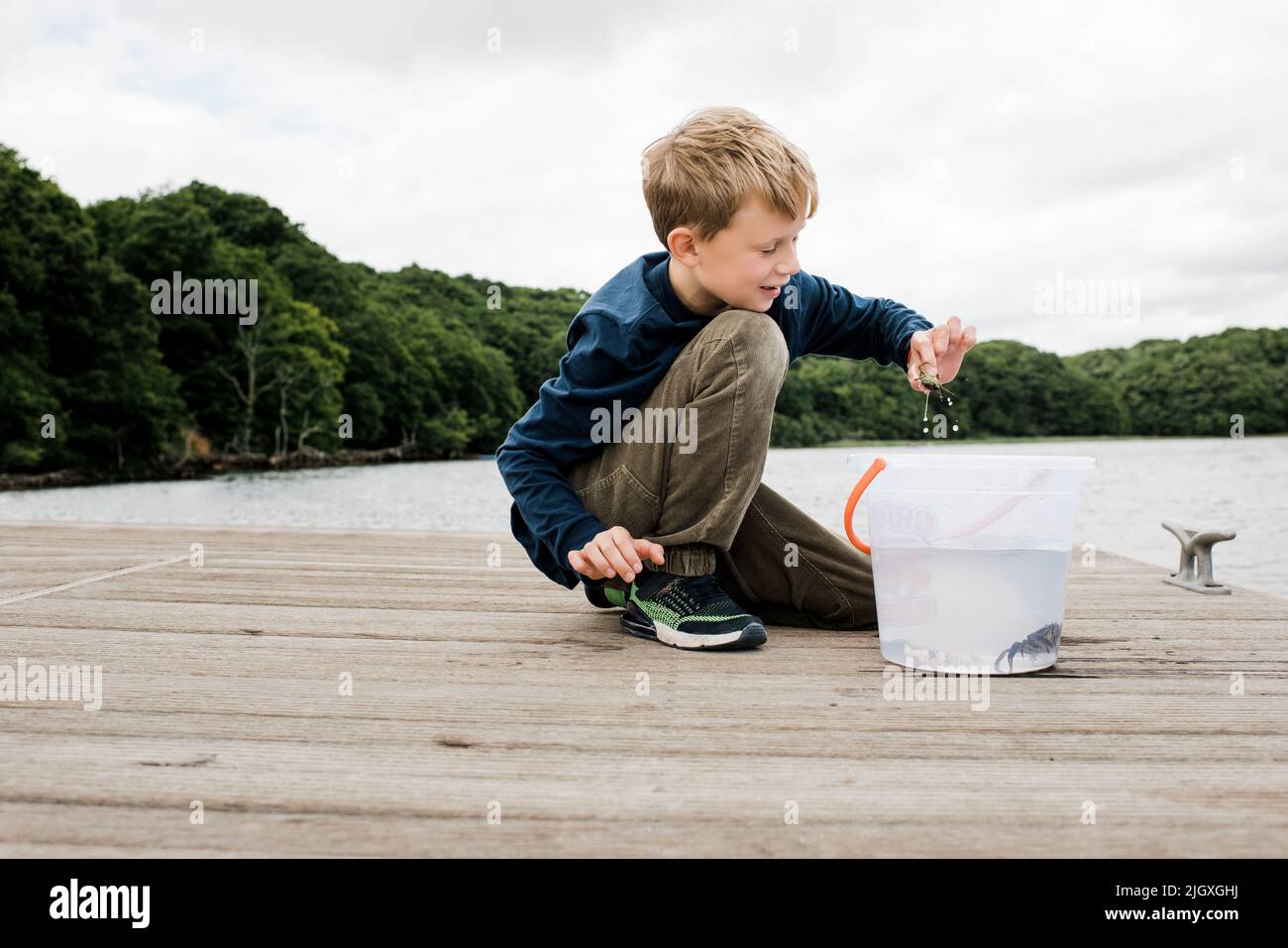 boy happily holding a crab that he caught whilst fishing on the dock Stock Photo