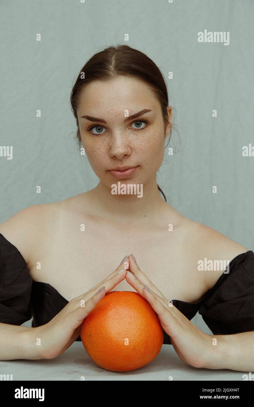 Young woman with freckles holding palms on grapefruit Stock Photo