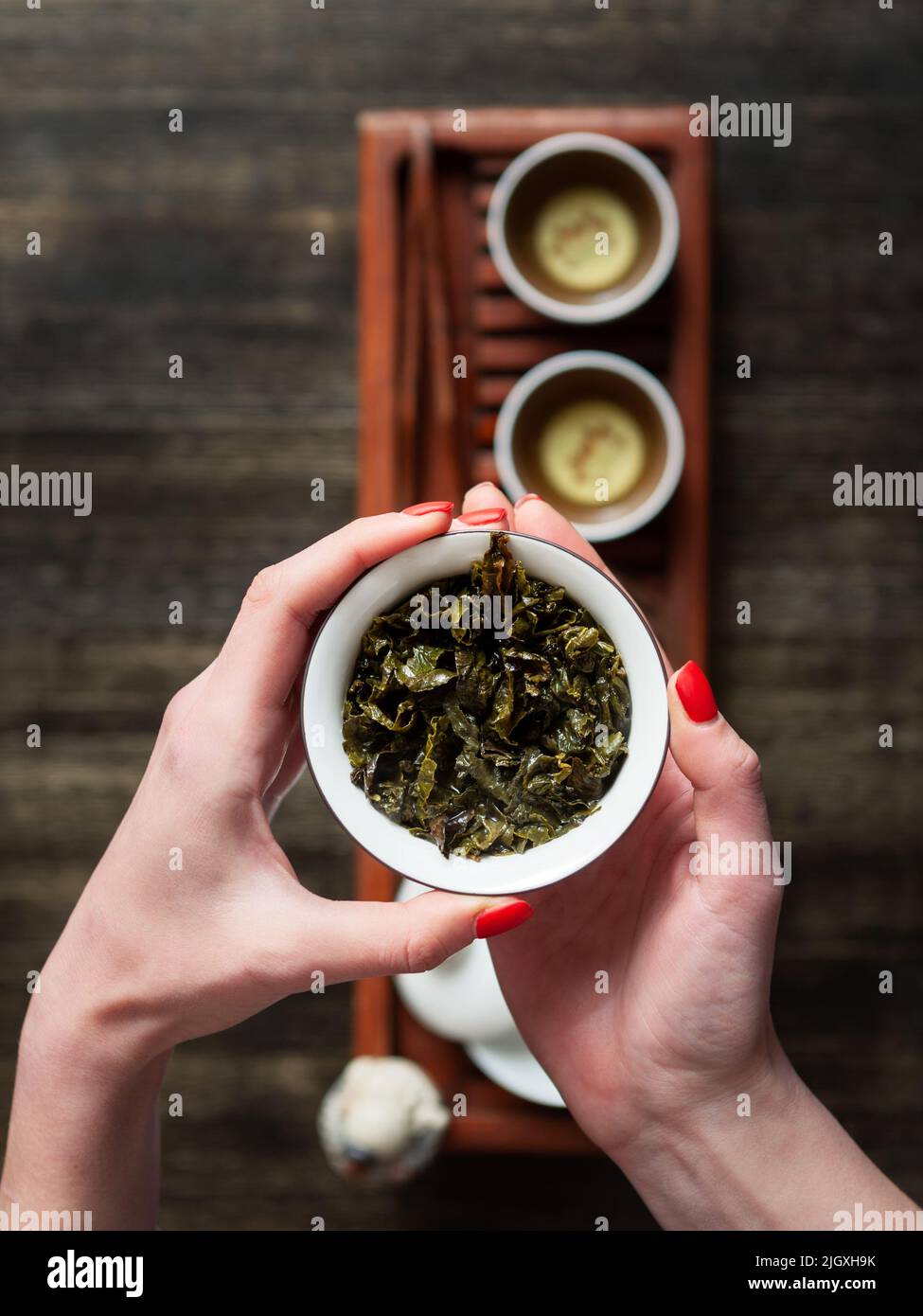 Hands holding Chawan (tea bowl) with green oolong. Top view shot. Stock Photo