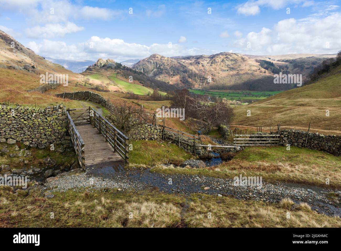 A bridge over Scaleclose Gill with Castle Crag and Grange Fell beyond at Borrowdale in the Lake District National Park, Cumbria, England. Stock Photo